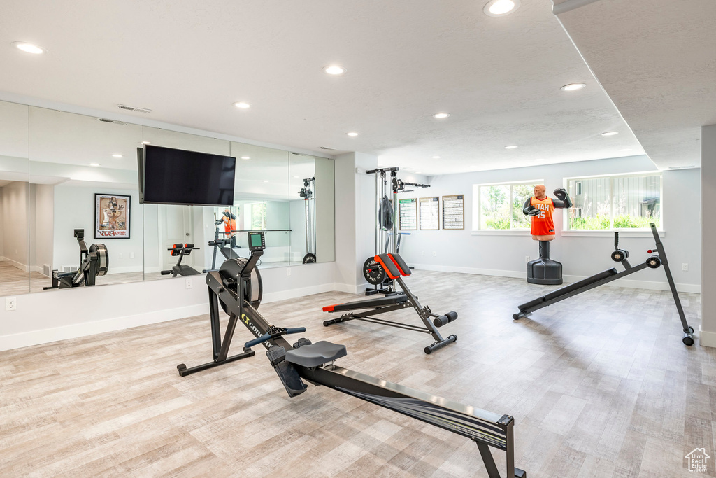 Exercise room with light wood-style floors, baseboards, and recessed lighting