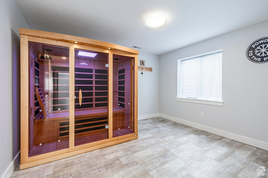Relaxing sauna / steam room with baseboards and wood finished floors