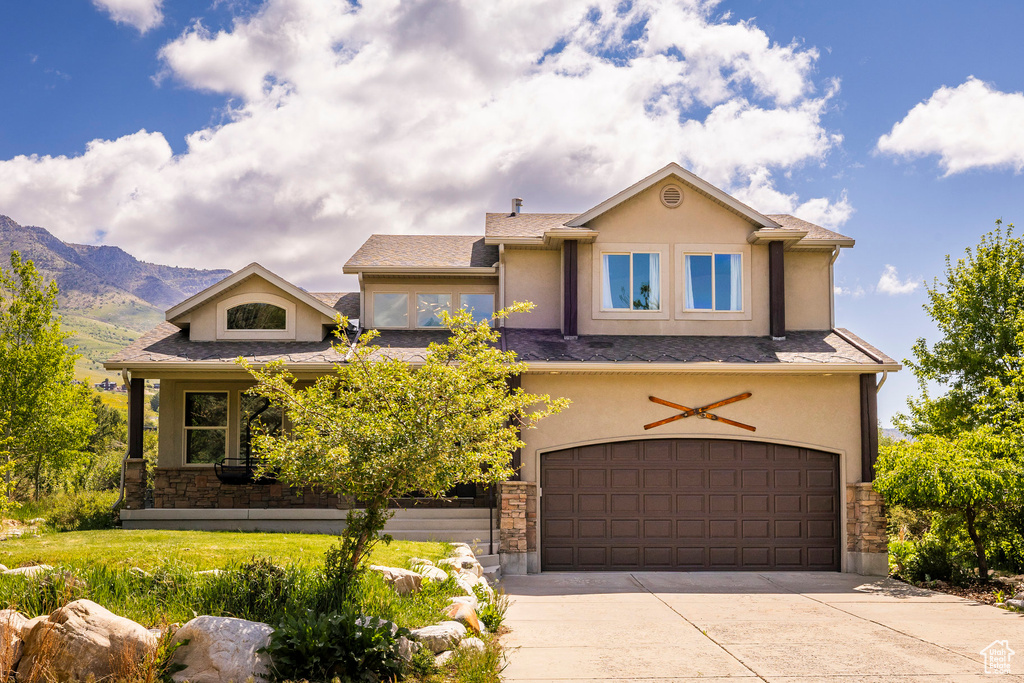 View of front of home featuring stone siding, stucco siding, concrete driveway, a garage, and a mountain view