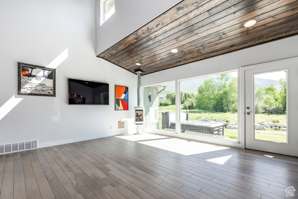 Unfurnished living room with wood ceiling, wood finished floors, and a towering ceiling
