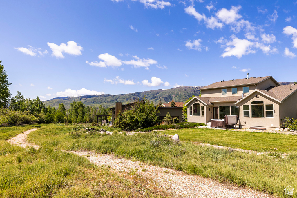 Back of property featuring a mountain view, stucco siding, and a patio area