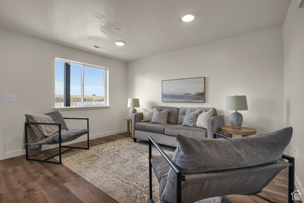 Living area with baseboards, dark wood-type flooring, and recessed lighting
