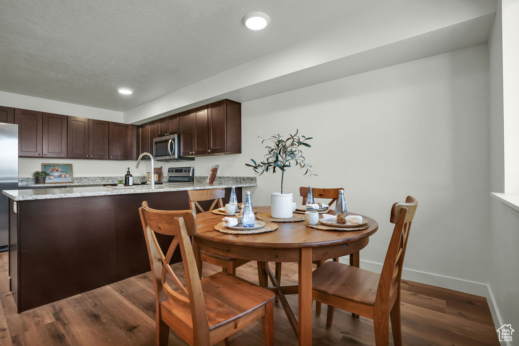 Dining space featuring dark wood-style flooring, recessed lighting, baseboards, and a textured ceiling