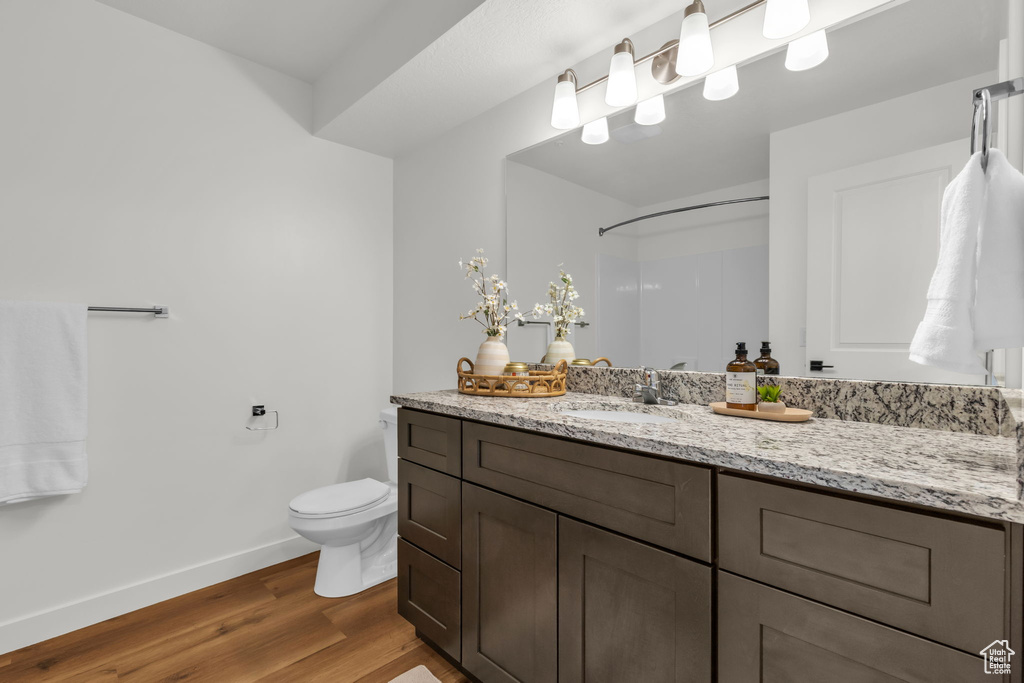Bathroom featuring wood finished floors, toilet, baseboards, and vanity