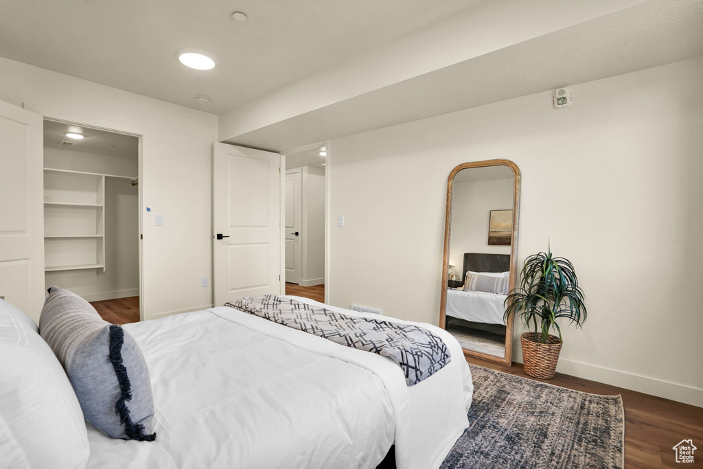 Bedroom featuring baseboards, wood finished floors, a walk in closet, and a closet