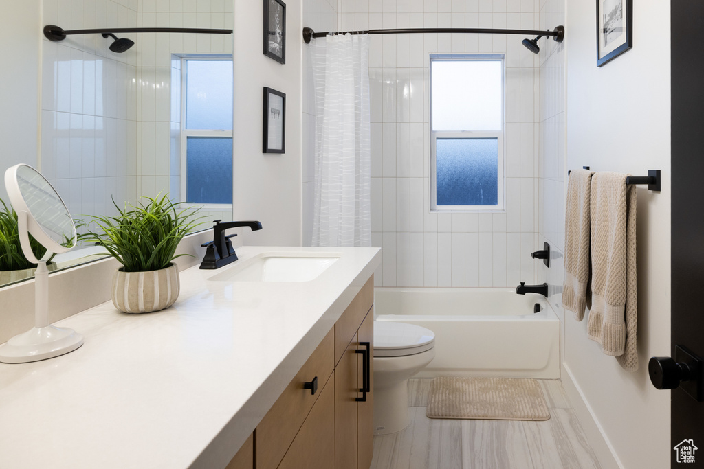 Bathroom with shower / bathtub combination with curtain, toilet, and vanity