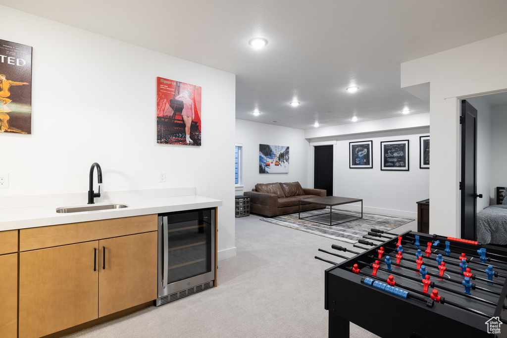 Bar area featuring a sink, beverage cooler, light carpet, recessed lighting, and baseboards