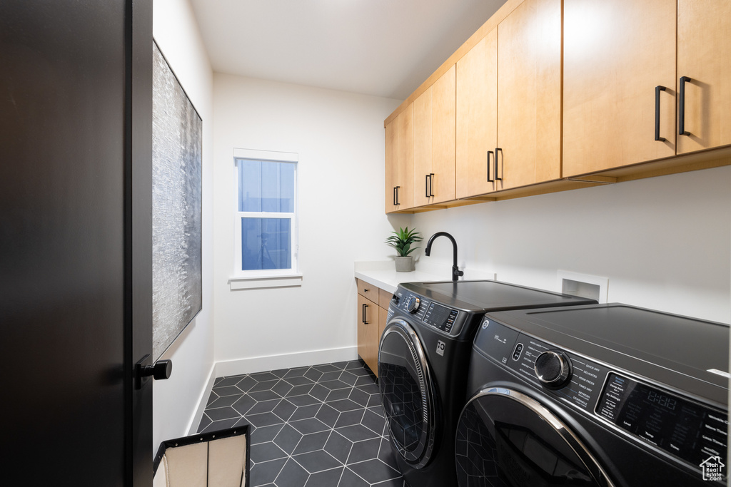 Laundry room featuring separate washer and dryer, cabinet space, baseboards, and dark tile patterned flooring