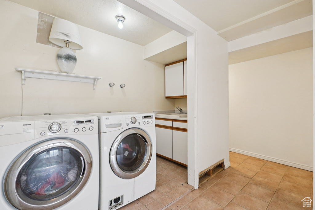 Laundry area with washer and clothes dryer, cabinet space, and light tile patterned floors
