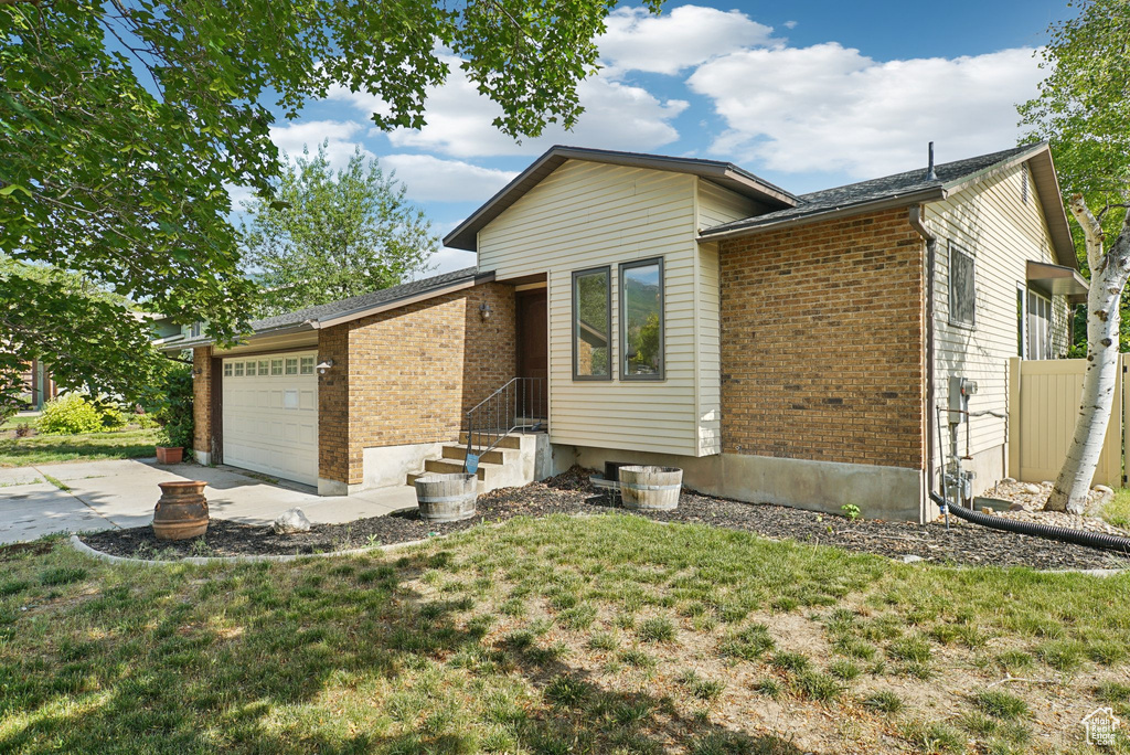 View of front facade featuring a garage, brick siding, driveway, and a front lawn