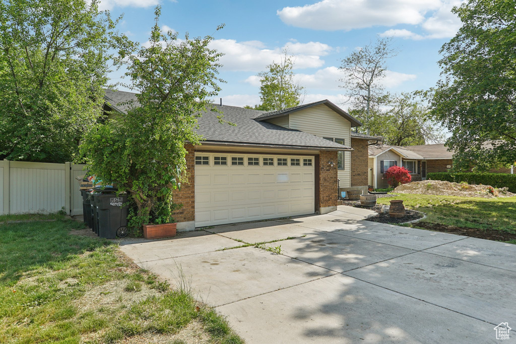View of front facade with brick siding, concrete driveway, a shingled roof, and a garage