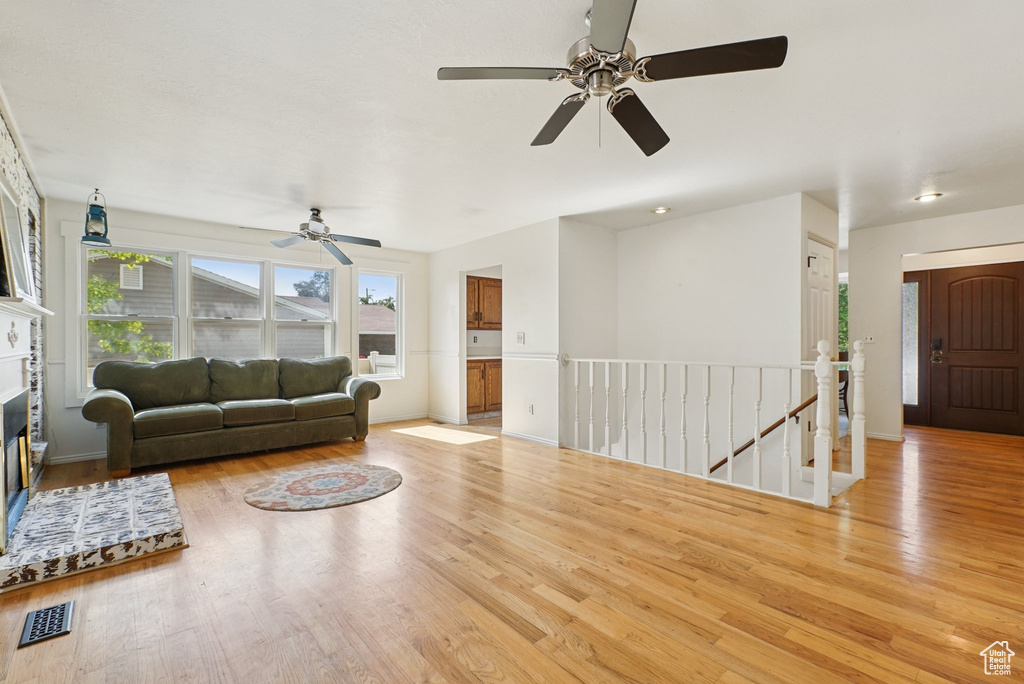 Living area featuring wood finished floors, a ceiling fan, a glass covered fireplace, and baseboards