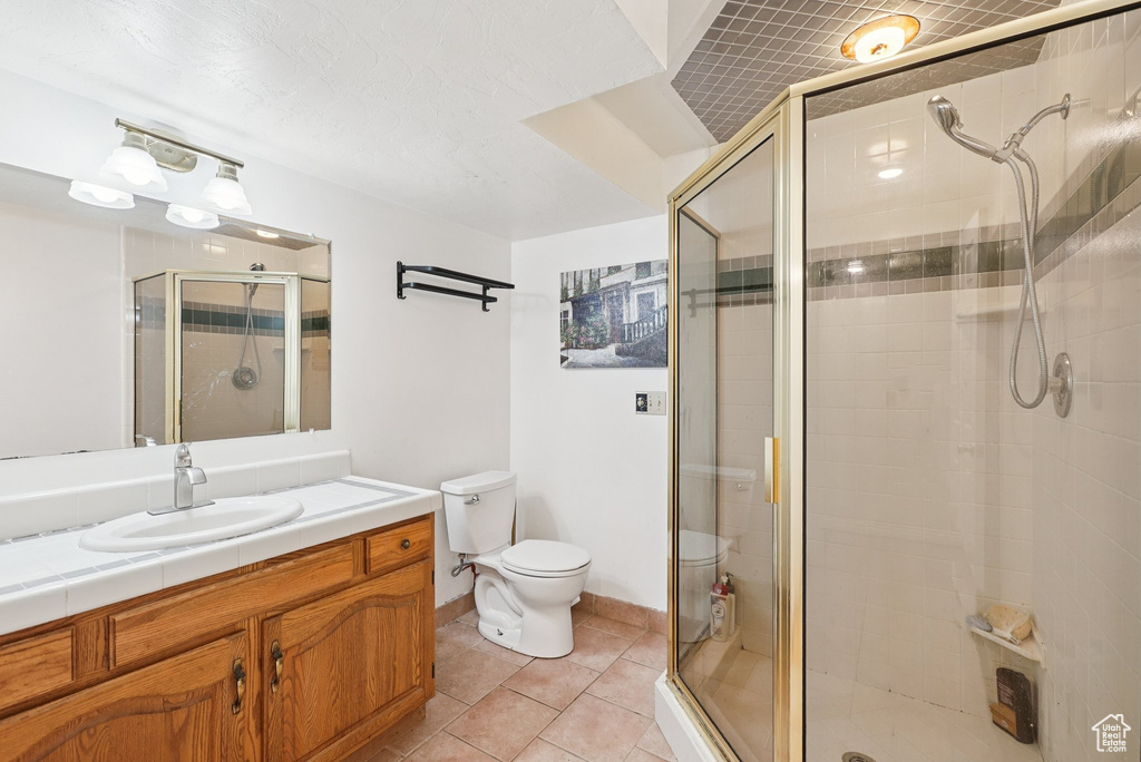Full bath with toilet, vanity, a shower stall, and tile patterned flooring