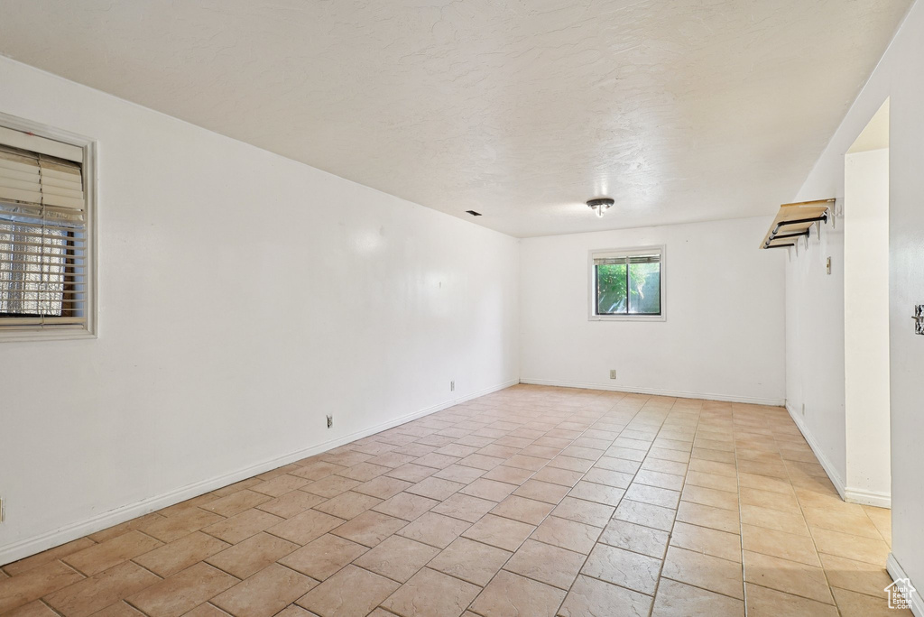 Unfurnished room with light tile patterned flooring and baseboards