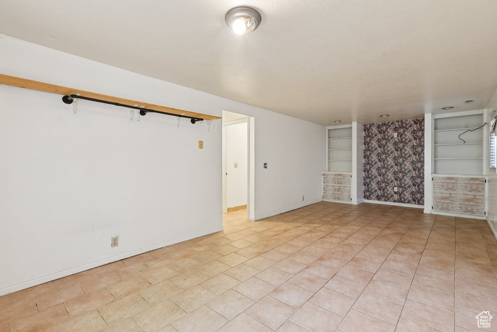 Unfurnished room featuring built in shelves and baseboards