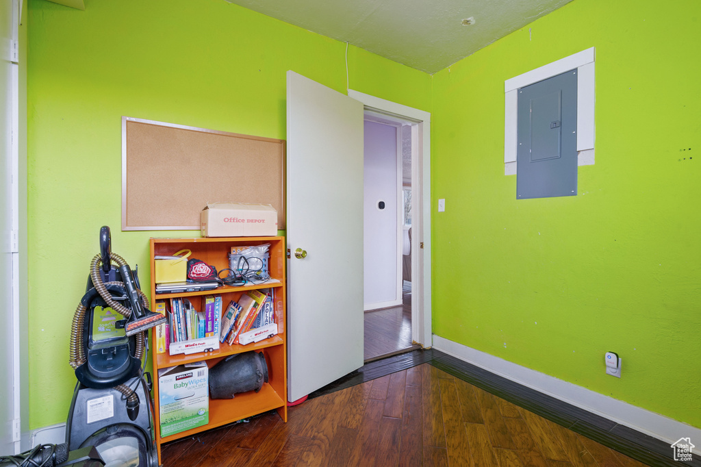 Interior space with electric panel, wood finished floors, and baseboards