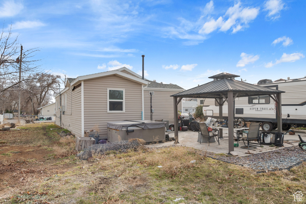 Back of property with a gazebo, a patio, and a hot tub