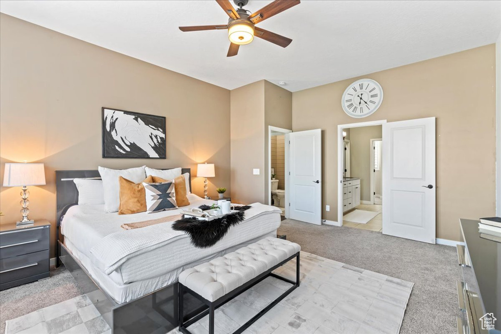 Bedroom featuring light colored carpet, ensuite bathroom, baseboards, and ceiling fan