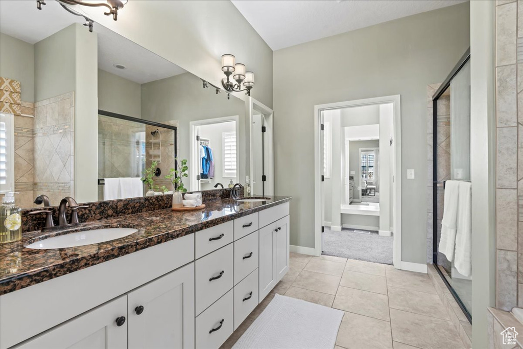 Bathroom featuring a shower stall, tile patterned floors, double vanity, and baseboards
