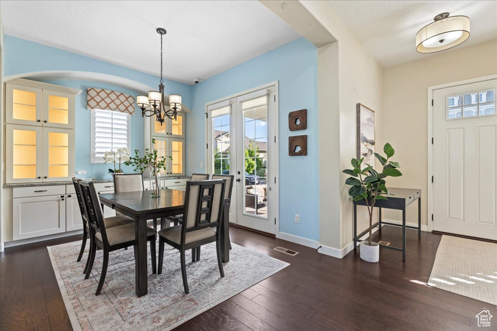 Dining room with plenty of natural light, a chandelier, and dark wood-type flooring