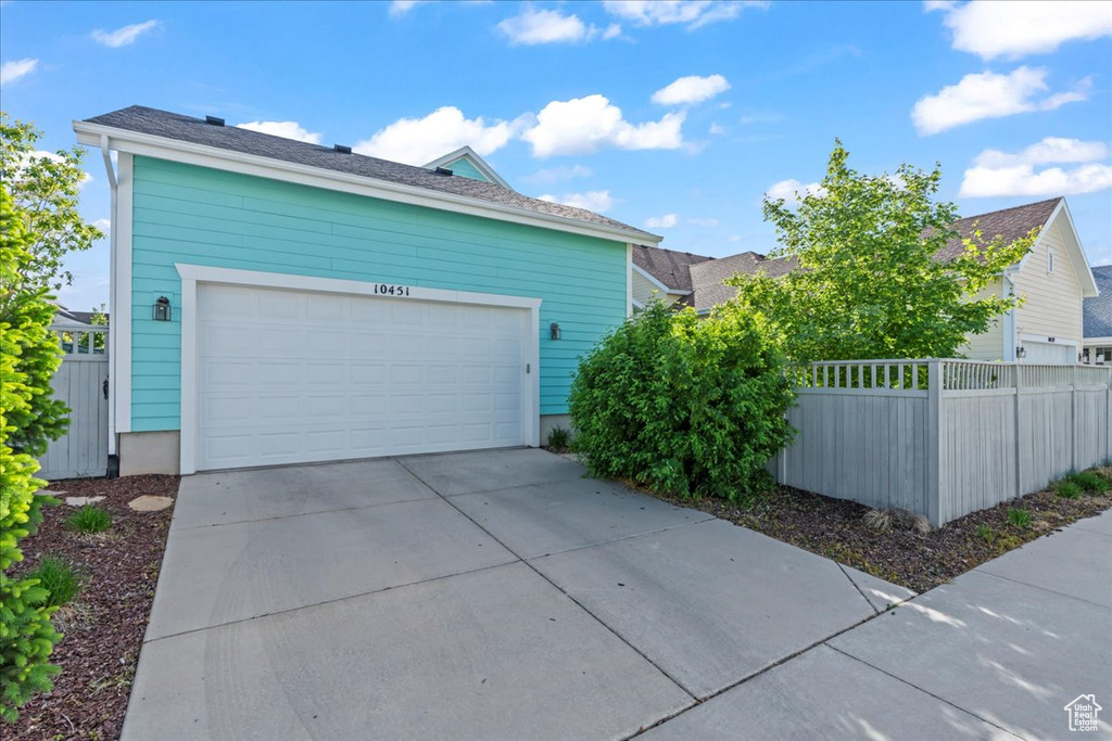 View of property exterior with fence, concrete driveway, and a garage