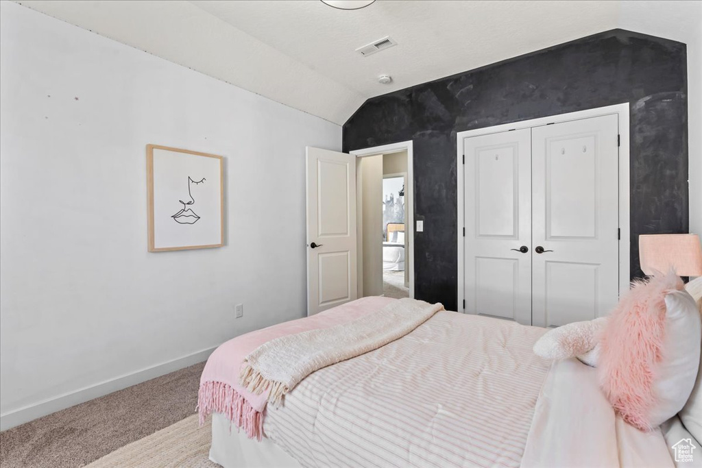 Bedroom with lofted ceiling, carpet flooring, baseboards, and a closet