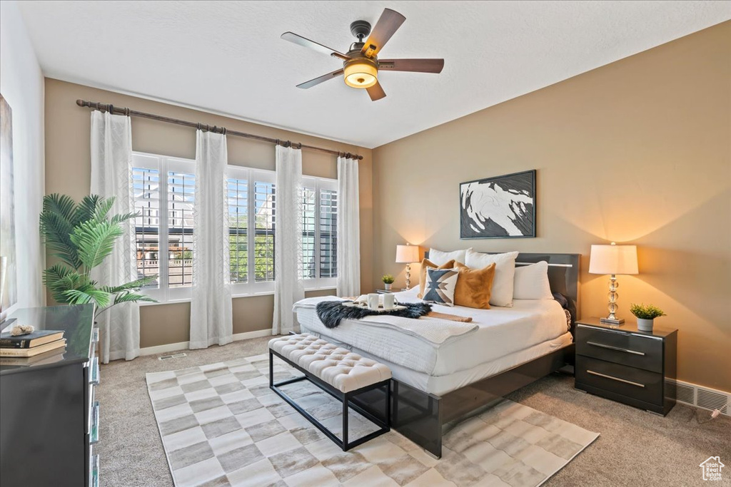 Bedroom featuring light colored carpet, baseboards, and a ceiling fan