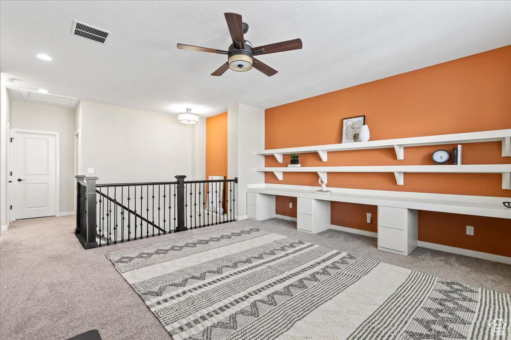 Unfurnished office featuring carpet flooring, a ceiling fan, built in study area, and baseboards