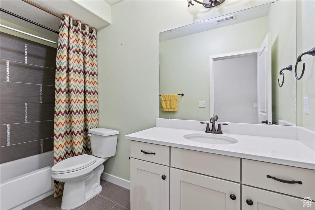 Full bath with toilet, vanity, tile patterned floors, shower / bathtub combination with curtain, and baseboards