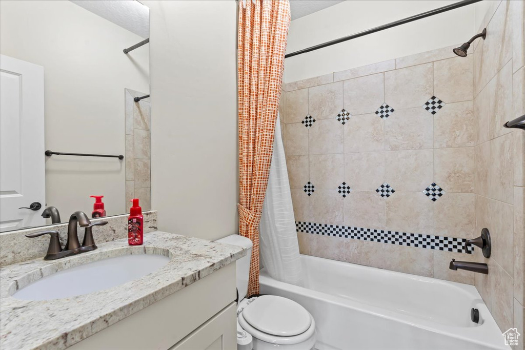 Full bath with shower / bath combo with shower curtain, vanity, and toilet