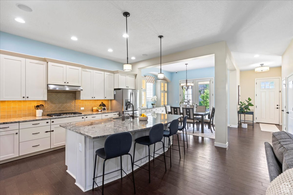 Kitchen with stainless steel appliances, a sink, a kitchen breakfast bar, decorative backsplash, and recessed lighting