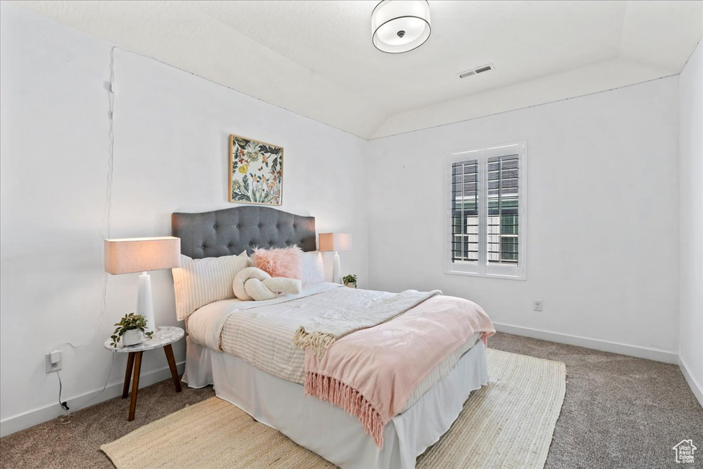 Carpeted bedroom with lofted ceiling and baseboards