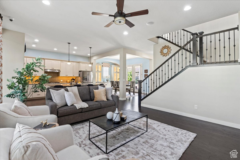 Living room with recessed lighting, baseboards, ceiling fan, wood finished floors, and stairway