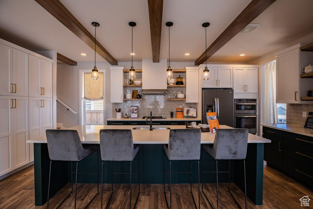 Kitchen featuring open shelves, stainless steel appliances, tasteful backsplash, light countertops, and beamed ceiling