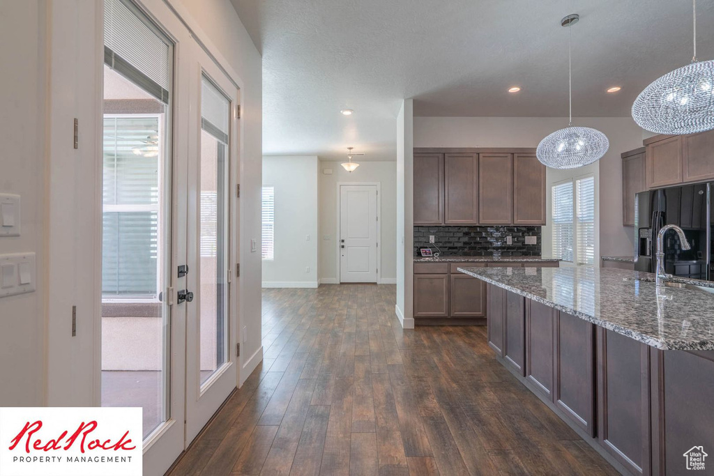 Kitchen featuring black refrigerator with ice dispenser, healthy amount of natural light, baseboards, dark wood-style floors, and recessed lighting