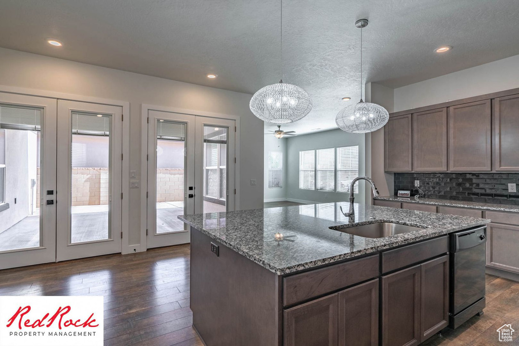 Kitchen with french doors, a sink, dishwasher, dark wood-type flooring, and dark stone counters