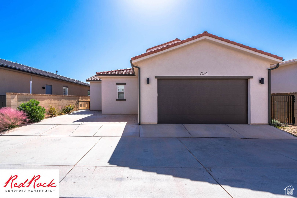 Mediterranean / spanish home with stucco siding, a tile roof, an attached garage, and concrete driveway