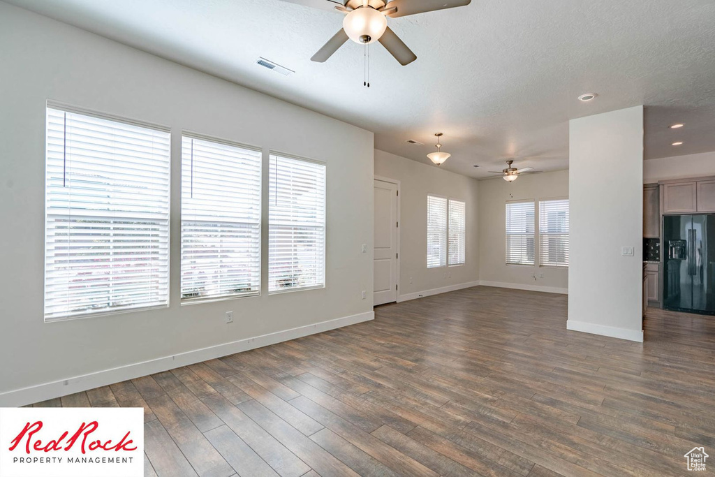 Unfurnished living room with ceiling fan, dark wood-style floors, baseboards, and recessed lighting