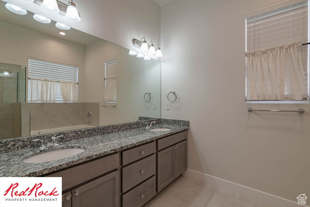 Bathroom featuring tile patterned floors, baseboards, a garden tub, and double vanity