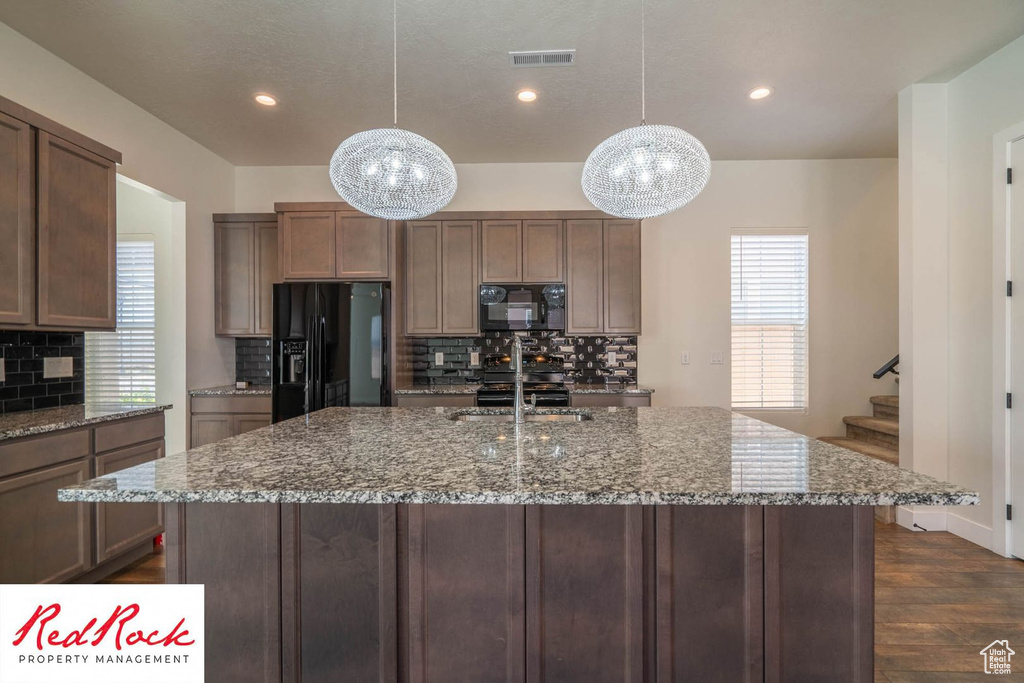 Kitchen featuring black appliances, a chandelier, a sink, dark wood-type flooring, and tasteful backsplash