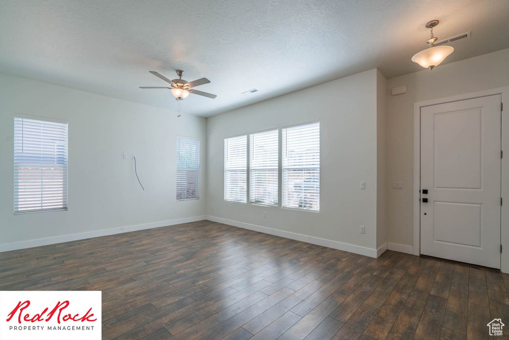Spare room with a ceiling fan, baseboards, dark wood-style floors, and a textured ceiling