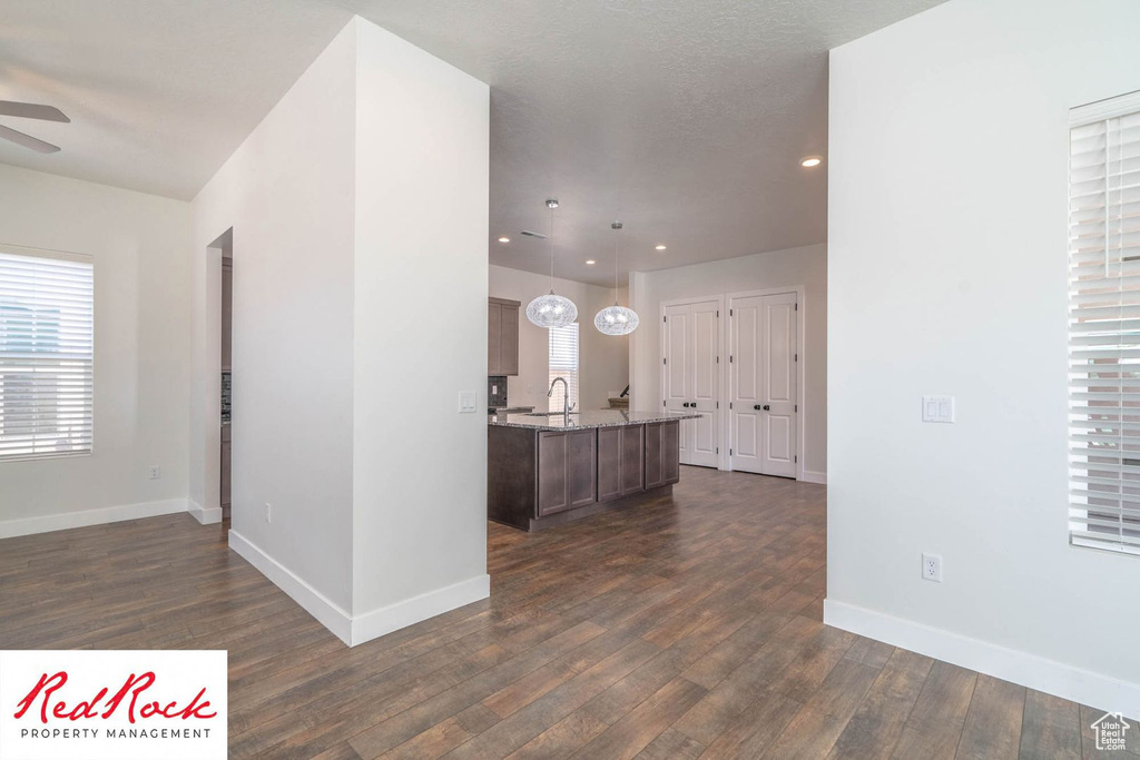 Kitchen with dark wood-style floors, a ceiling fan, light stone counters, baseboards, and recessed lighting