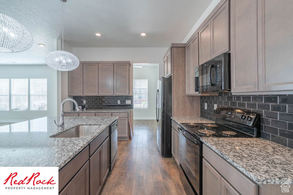 Kitchen featuring black appliances, a sink, tasteful backsplash, hardwood / wood-style flooring, and a chandelier