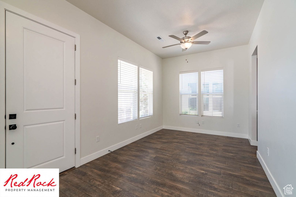 Empty room featuring dark wood-style floors, ceiling fan, and baseboards