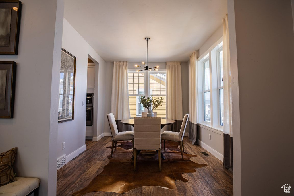Dining space featuring a chandelier, baseboards, dark wood-type flooring, and plenty of natural light