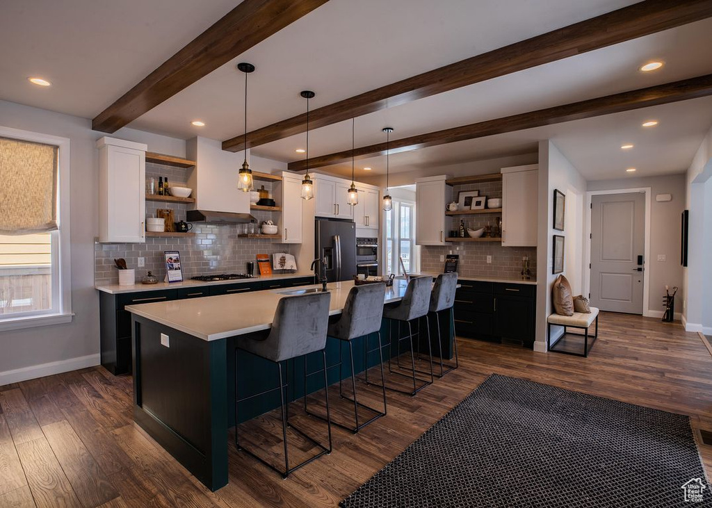 Kitchen with open shelves, stainless steel appliances, baseboards, white cabinets, and a kitchen bar