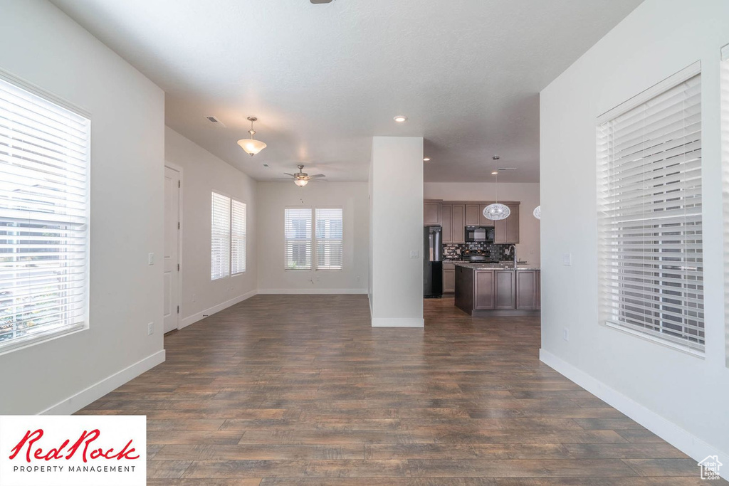 Unfurnished living room with ceiling fan, dark wood finished floors, baseboards, and recessed lighting