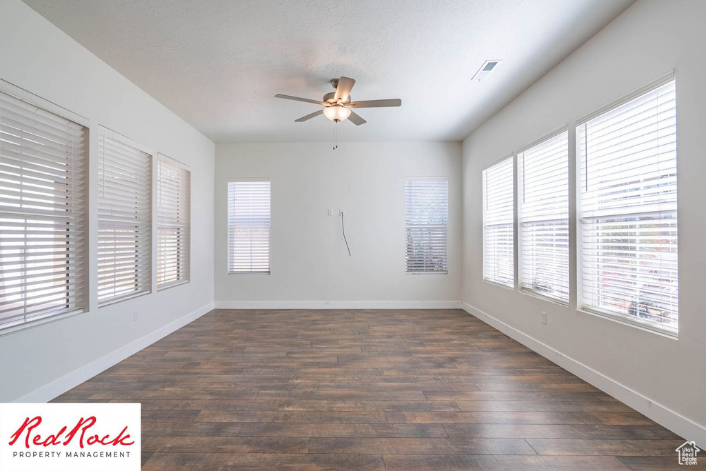 Unfurnished room with a ceiling fan, dark wood-style floors, and baseboards