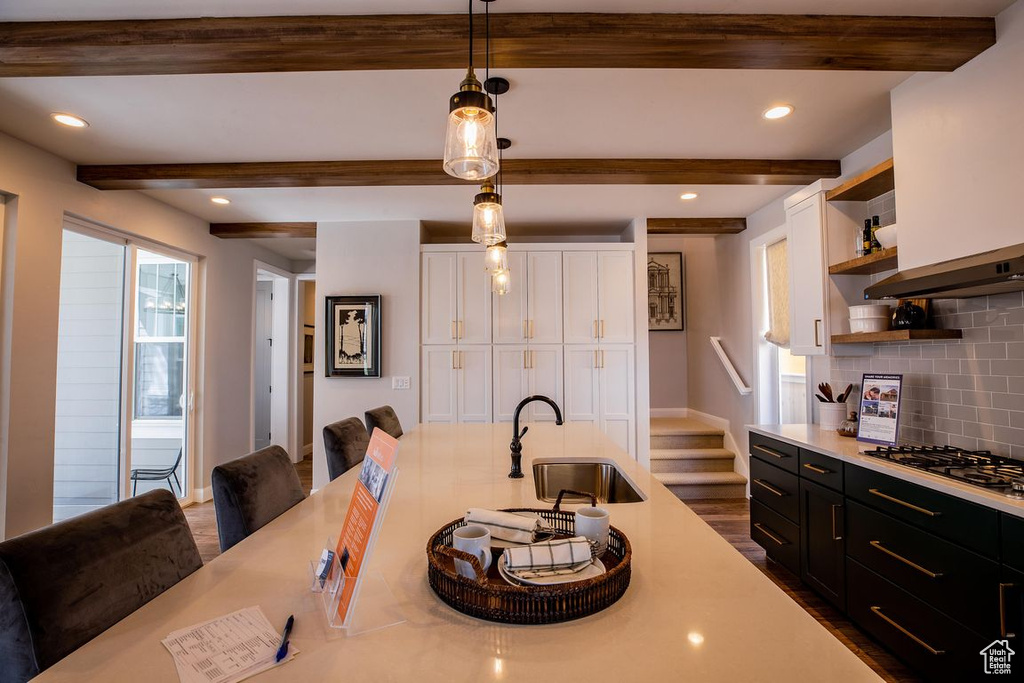 Kitchen featuring a sink, open shelves, white cabinetry, light countertops, and gas cooktop