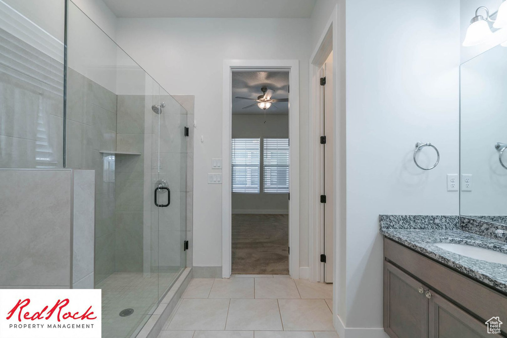 Full bath with tile patterned flooring, ceiling fan, a stall shower, vanity, and baseboards